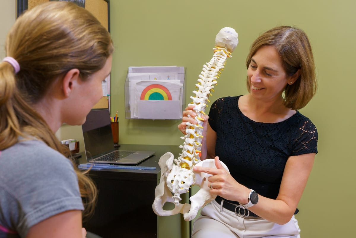 A physiotherapist explaining the spine and pelvis to a patient using an anatomical model